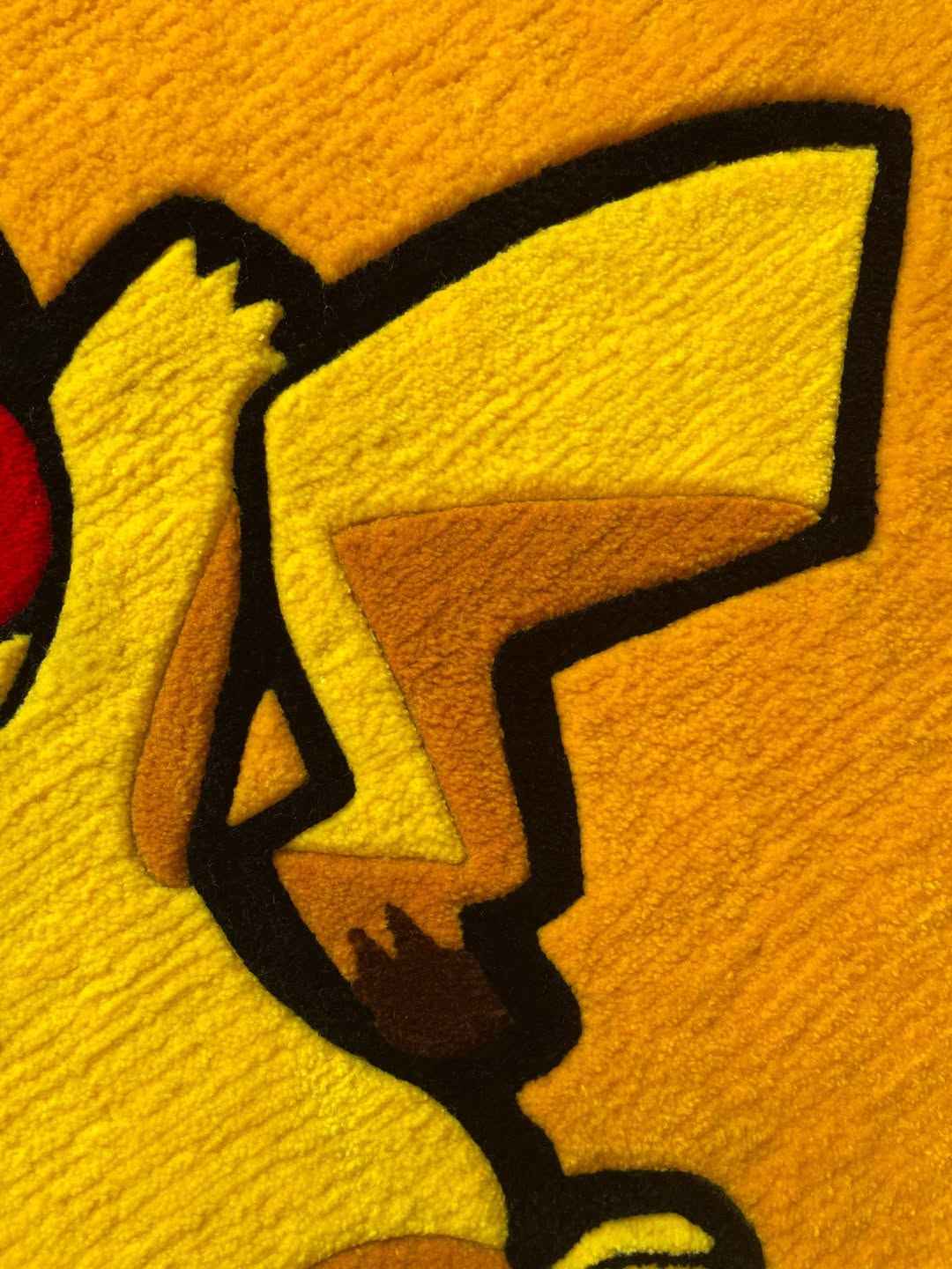 Close-up Pikachu rug side: black outlines and yellow body fur texture with tan inner details