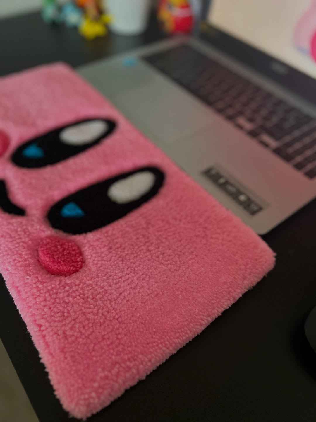 Pink plush keyboard wrist rest rug with Kirby face close-up, black eyes and blue pupils