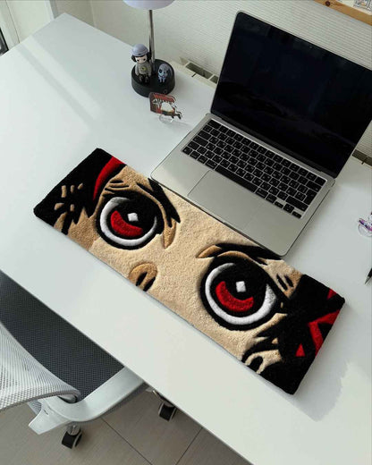 Handmade anime tufted desk mat laid on desk with two large red eyes and black details