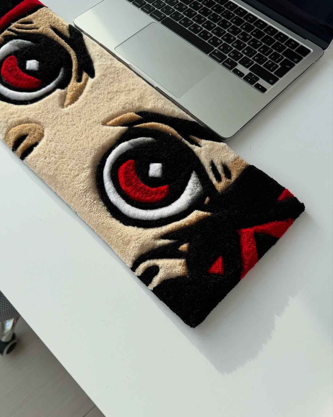 Handmade anime tufted desk mat featuring red eye graphic with black accents on tan