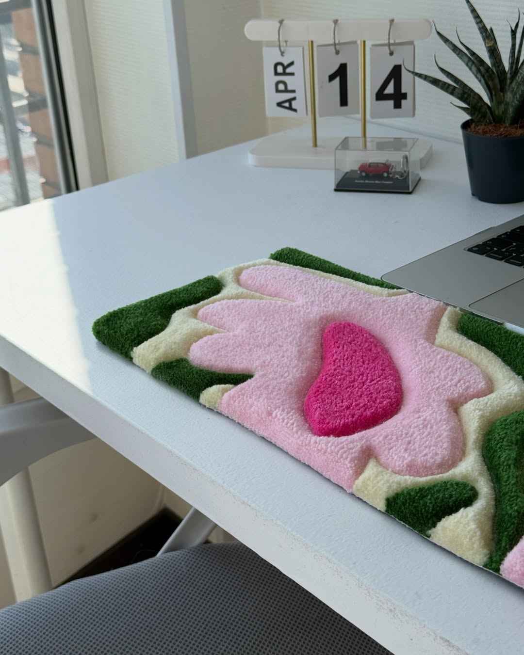 Handmade tufted floral desk mat with green edges and pink flower shapes