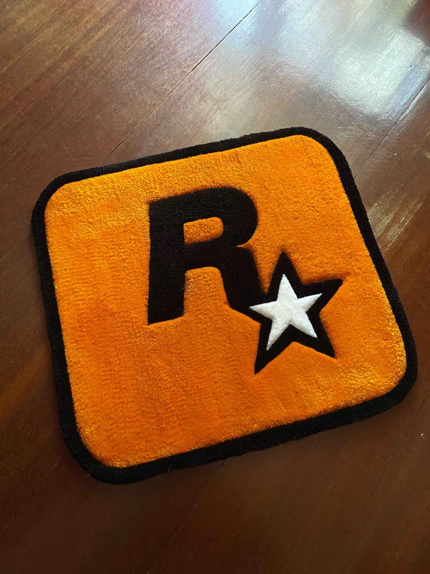 Yellow gaming rug with black border and R* logo, star accents, rounded corners