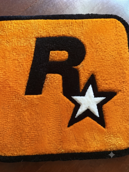 Yellow gaming rug with large black R and white star detail, black edge border